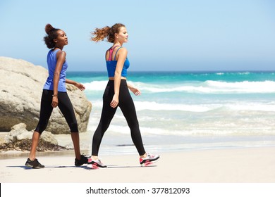 Side portrait of two young sporty women walking on the beach
