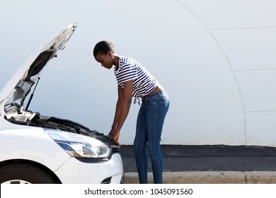 Side Portrait Of Young African American Woman Looking Under The Hood Of Broken Down Car