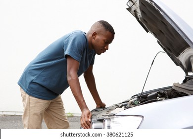 Side portrait of young african man looking under the hood of car