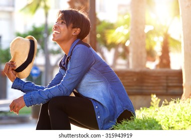 Side Portrait Of A Young Black Woman Smiling Outside In Park