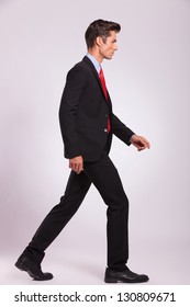 Side Portrait Of A Young Business Man Walking On Gray Background And Looking Away