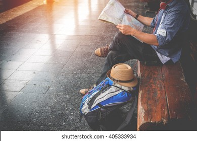 Side Portrait Of A  Young Man Traveler Sitting With Map Choose Where To Travel And Bag Waiting For Train, Vintage Tone Filter Effected