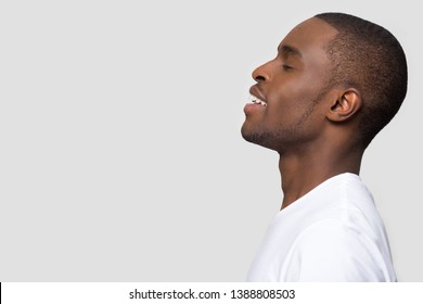 Side profile african male standing on grey background aside copyspace for your advertisement text. Positive american guy closed eyes enjoy fresh air make deep breath, dreaming feels peaceful concept
