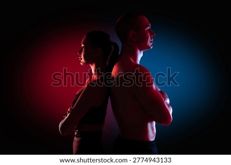 Side profile of athletic couple back to back with shirtless muscular man