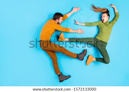 Side profile full length body size top above high angle view photo of crazy mad insane couple of karatists girl kicking man away with leg casually screaming rageously isolated pastel blue background