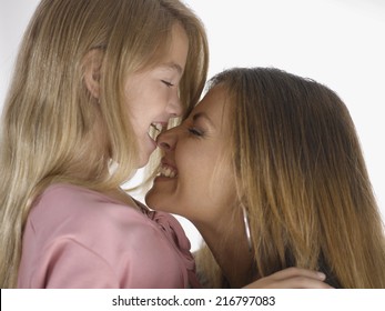 Side profile of a girl biting her mother's nose and smiling - Shutterstock ID 216797083