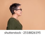 Side profile photo of nice woman with short hair dressed sweater in glasses look at sale empty space isolated on beige color background