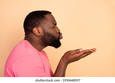 Side profile photo portrait of man sweet romantic sending air kiss to copyspace isolated pastel beige color background