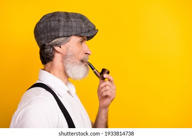 Side profile photo portrait of senior gentleman smoking tobacco wooden pipe isolated vivid yellow color background copyspace