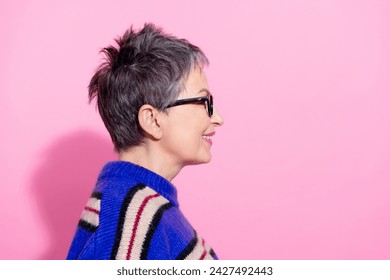 Side profile photo of positive cheerful woman wear striped pullover in glasses look at logo empty space isolated on pink color background - Powered by Shutterstock