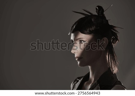 Side profile portrait emphasizing creative avant garde hairstyle and professional hair styling. Editorial beauty concept with dramatic studio lighting.