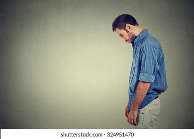 Side profile sad lonely young man looking down has no energy motivation in life depressed isolated on gray wall background