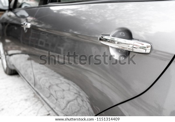 Side profile of a sedan. Angle\
from rear door to front. In silver tone and silver grey car\
paint.