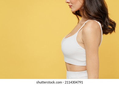 Side profile view cropped close up photo shot young brunette caucasian woman 20s wearing white brassiere underwear isolated on plain yellow color background studio portrait. Plastic surgery concept