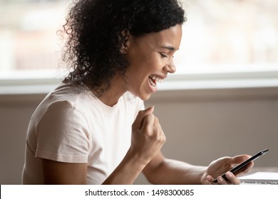 Side Profile View Of Excited Mixed Race Ethnicity Woman Hold Cellphone Triumph Get Good Text Message, Overjoyed African American Female Win Online Lottery On Smartphone, Get Promotion Email On Cell