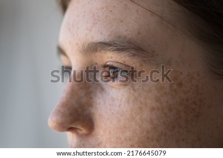 Side profile view face of freckled serious pensive woman staring aside. Close up cropped image of thoughtful young 18s female looking into distance. Concept of vision care, eyesight check up in clinic