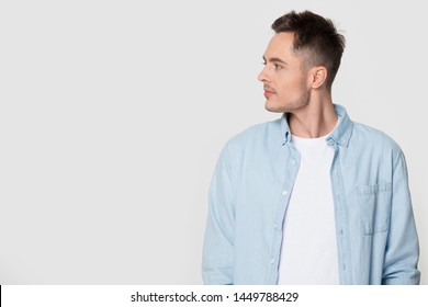 Side profile view of man looking at empty copy space. Studio photoshoot of stylish male turning head aside watching to blank gray background. Advertisement banner, editable promotion, sale concept
