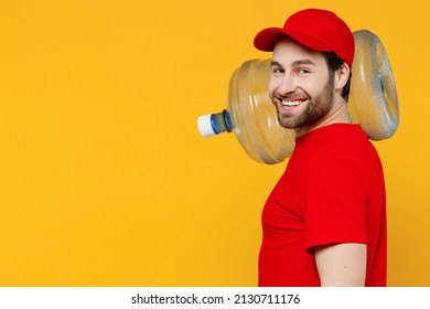 SIde profile view rofessional delivery guy employee man in red cap T-shirt uniform workwear work as dealer courier hold water bottle isolated on plain yellow background studio portrait Service concept