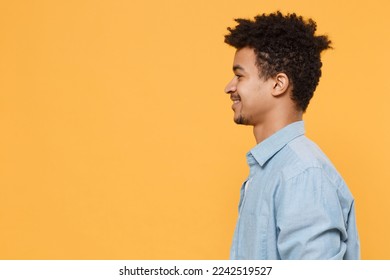 Side profile view smiling young man of African American ethnicity he wear casual blue shirt look aside isolated on yellow background studio portrait. People sincere emotions lifestyle concept. Mock up - Shutterstock ID 2242519527