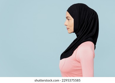 Side profile view young calm arabian asian muslim fitness trainer sporty woman wearing pink abaya hijab spend time in home gym isolated on plain blue background studio. Workout sport fit abs concept - Powered by Shutterstock