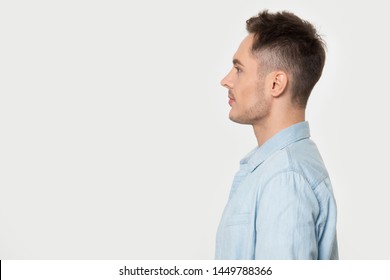 Side profile view young confident European guy looking at blank empty copy space for advertisement text, isolated on grey white studio background, free place for product or service offer.