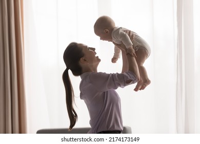 Side Profile View, Young Mother Lifts Her 0-6 Baby, Carefree Family Having Fun At Home, Play Active Games, Laughing Enjoy Priceless Time Together Indoor. Happy Motherhood, Childcare, Babyhood Concept