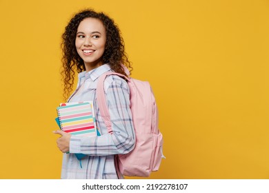 Side Profile View Young Smart Fun Happy Black Teen Girl Student She Wearing Casual Clothes Backpack Bag Holding Books Isolated On Plain Yellow Color Background. High School University College Concept