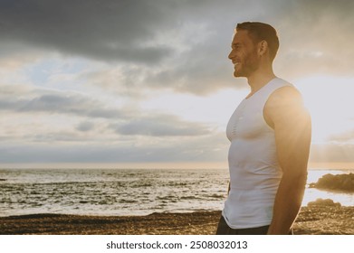 Side profile view young strong sporty athletic toned fit sportsman man he wear sports clothes look aside warm up training at sunrise sun dawn over sea beach outdoor on seaside in summer day morning - Powered by Shutterstock