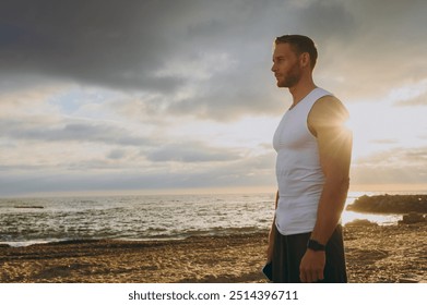 Side profile view young strong sporty athletic toned fit sportsman man he wearing sports clothes look aside warm up train at sunrise sun dawn over sea beach outdoor on seaside in summer day morning - Powered by Shutterstock