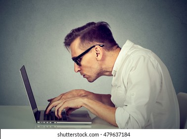 Side Profile Young Man In Glasses Working On Computer Sitting At Desk Isolated On Gray Wall Office Background. Long Monotonous Tiresome Working Hours Life Concept