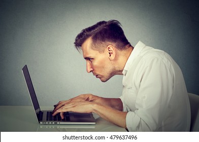 Side Profile Young Man Working On Computer Sitting At Desk Isolated On Gray Wall Office Background. Long Monotonous Tiresome Working Hours Life Concept