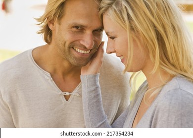 Side Profile Of A Young Woman Touching A Young Man's Face And Smiling