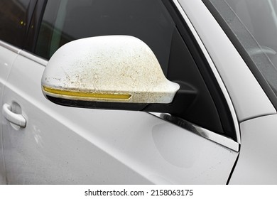 Side Rear View Mirror On Driver Door Covered With A Layer Of Adhered Dirt To A White Dirty Car With Yellow Turn Signals On The Outside Mirror Body Close-up, Nobody.