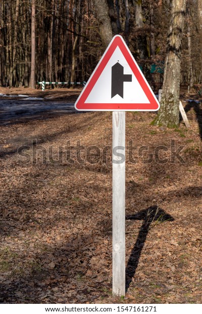 Side road right sign on a stand in the road\
through the forest.