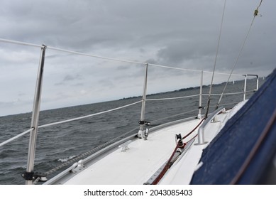 a side of a sailboat on the seawater in the Netherlands. a sailboat deck on the waves of the sea under grey skies.part of the curved sailing sailboat. safety fence on the sailboat deck.sniping scene.
