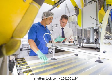 Side shot of an Engineer and a Technician working on coating glass for use in production of solar panels