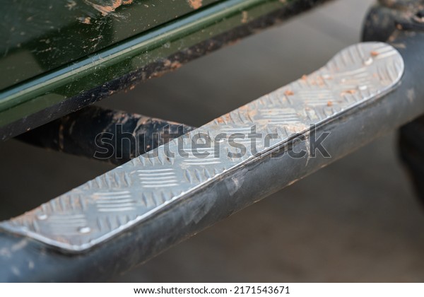 Side step with anti-slip metal plate assessory\
part on off-road truck car body. Transportation equipment object\
photo. Selective focus.