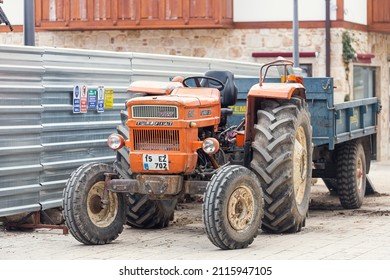 Side, Turkey -January 22, 2022: Old orange Tractor of brand Turk Fiat 640  is parked  on the street on a warm summer day against the backdrop of a buildung