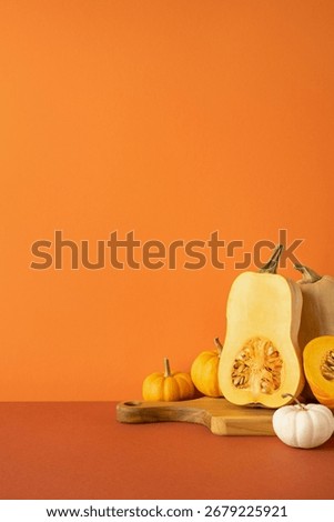 Side vertical view of squash and pumpkins arranged on a cutting board with orange background, evoking fall vibes, Thanksgiving traditions, and the harvest season