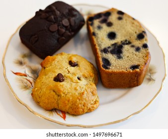 Side View Of 3 Vegan Cookies. Chocolate Cookie, Chocolate Chip Cookie And A Banana Bred With Blueberries. White Background. 