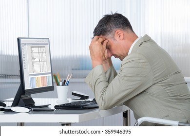 Side view of accountant suffering from headache at desk in office
