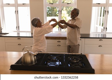 Side View Of An Active African American Senior Couple Dancing In The Kitchen At Home