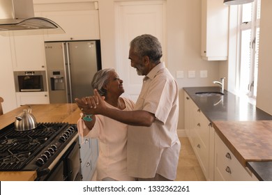 Side View Of An Active African American Senior Couple Dancing In The Kitchen At Home