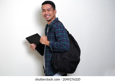 Side View Of Adult Asian Man Bring Backpack And Laptop Showing Happy Face Expression