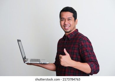 Side View Of Adult Asian Man Smiling Confident And Give Thumb Up While Holding A Laptop Computer
