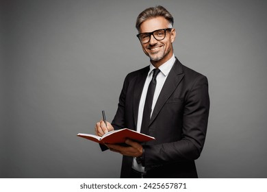 Side view adult fun successful employee business man corporate lawyer wear classic formal black suit shirt tie work in office write down in notebook isolated on plain grey background studio portrait - Powered by Shutterstock