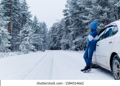 Side View Of Adult Woman Near Car Over Snowy Forest On Winter Roadtrip. Wanderlust Concept. Winter Travelling Scene.