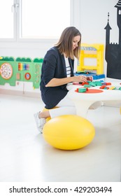 Side View Of Adult Woman Playing With Lego Bricks At Table