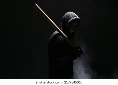 Side View Of African American Bandit In Hood Holding Wooden Baseball Bat On Black Background With Smoke