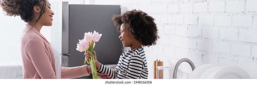 side view of african american child presenting fresh tulips to mom, banner - Powered by Shutterstock